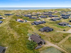 A coastal residential area with houses, some with attached garages, and a few with visible solar panels.