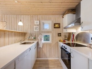Una cocina compacta con paneles de madera, horno empotrado y un lavamanos.