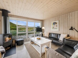 Una sala de estar acogedora con chimenea, un sofá, una mesita de centro y vistas al exterior.