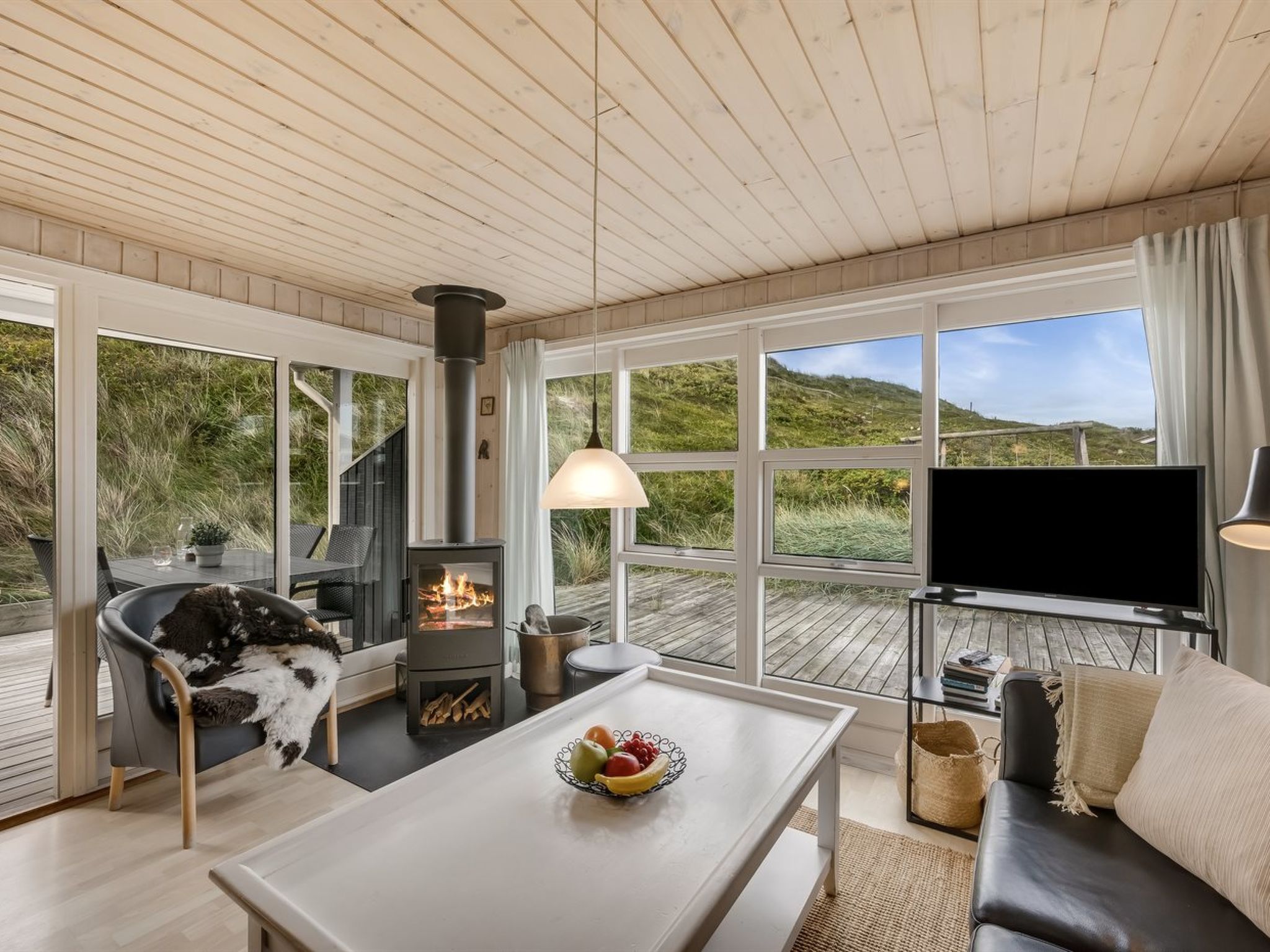 Una sala de estar acogedora con chimenea, un sofá, un televisor y una mesa de comedor.