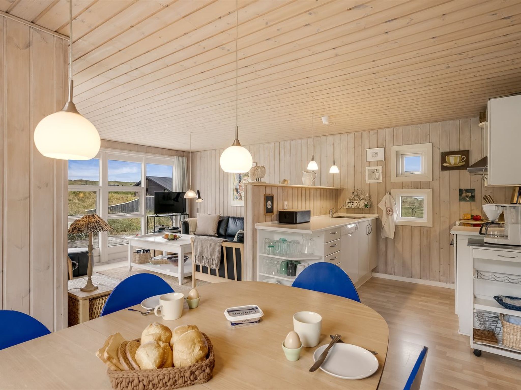 Una cucina moderna con mobili in legno, un'area pranzo con tavolo apparecchiato per due e vista sull'esterno.