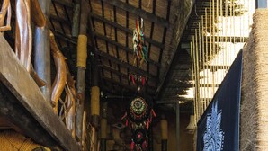 A rustic interior with wooden beams, a staircase, and various decorative items including masks and a tapestry. - Unwind Restaurant & Hostel (Seeduwa - Katunayake)