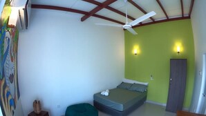 A bedroom with a bed, a ceiling fan, a green wall, and a door. - Unwind Restaurant & Hostel (Seeduwa - Katunayake)