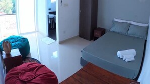 A bedroom with a bed, a wooden table, a wardrobe, and a ceiling fan. - Unwind Restaurant & Hostel (Seeduwa - Katunayake)