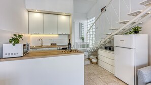 Una cocina moderna con armarios blancos, microondas, pileta y refrigerador.