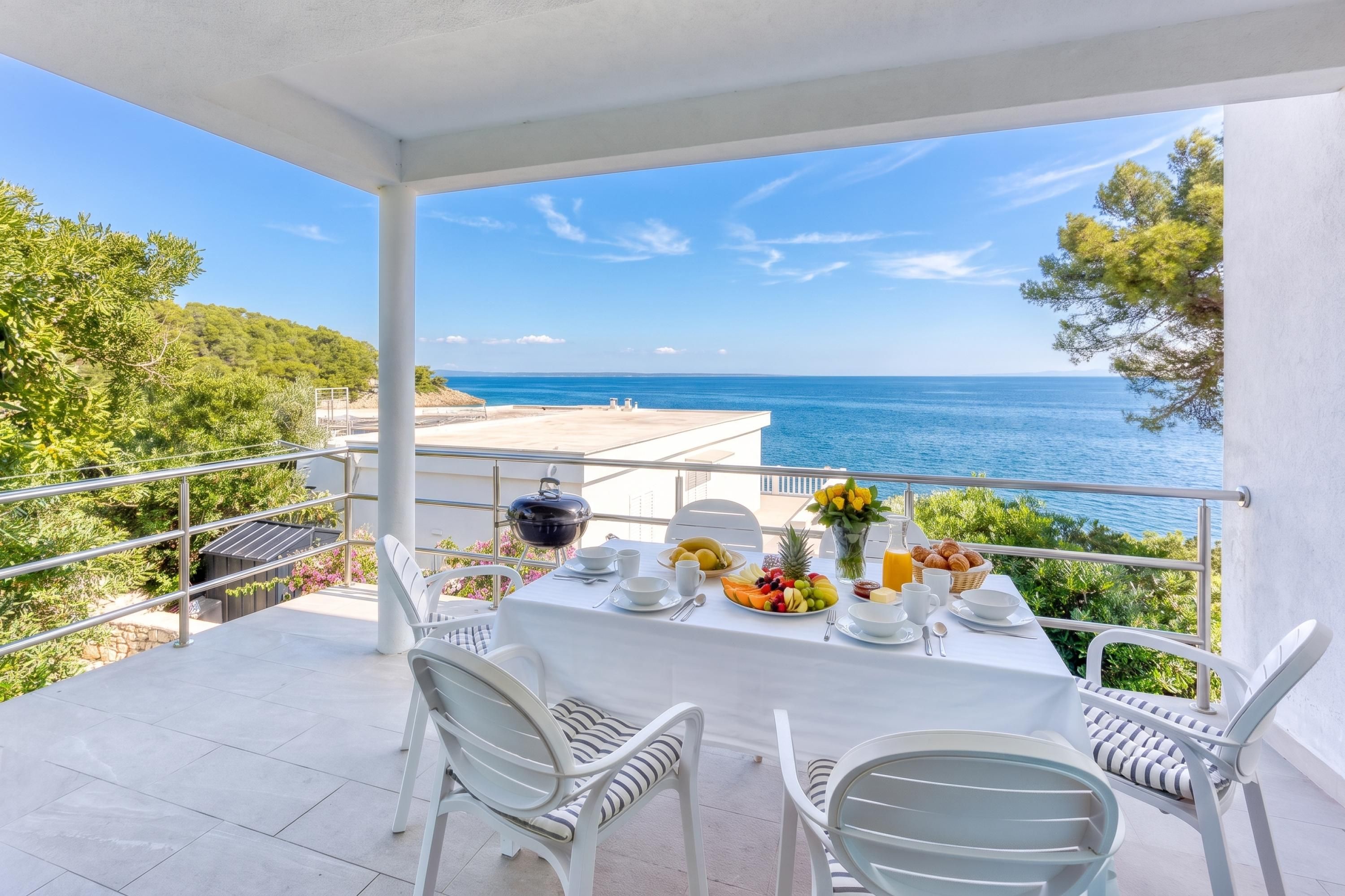 Un balcón con una mesa lista para el desayuno, con vistas al mar.