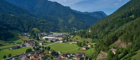 A mountainous village with residential buildings, a sports field, and a small church.
