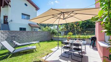 Un patio con sillones de descanso, una mesa y una sombrilla.