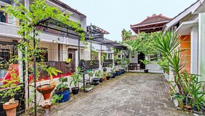 A courtyard with potted plants, a statue, and traditional architecture. - Hotel O Gita Graha Guest House Syariah (Yogyakarta)