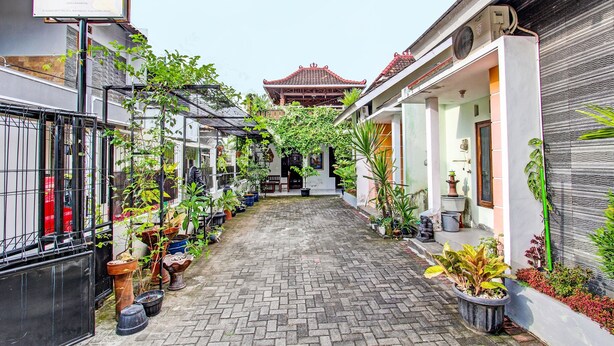 A narrow alleyway with potted plants and a traditional building in the background. - Hotel O Gita Graha Guest House Syariah (Yogyakarta)
