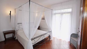 Una habitación con cama con dosel, una mesita de noche pequeña y un radiador.