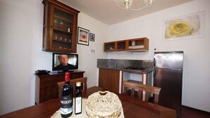 Una cocina con armarios de madera, encimera de granito, refrigerador de acero inoxidable y una mesa de comedor con una cesta y botellas.