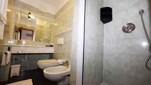 Baño con dos inodoros, un lavamanos y zona de ducha.