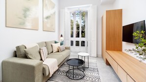 A modern living room with a sofa, a coffee table, a TV, and a patterned rug. - Candelaria10 - Apartamento Noble, a peaceful retreat within the heart of Cádiz (Cádiz)