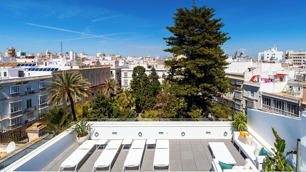 A rooftop terrace with sun loungers and a view of a cityscape. - Candelaria10 - Apartamento Noble, a peaceful retreat within the heart of Cádiz (Cádiz)