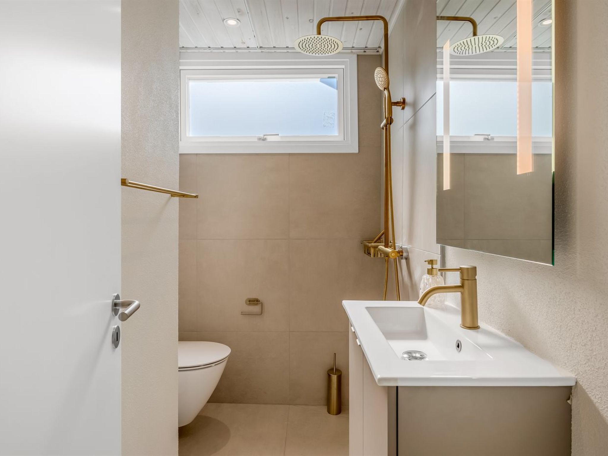 Un bagno moderno con un water bianco, un lavabo con dettagli dorati e una doccia con dettagli dorati.