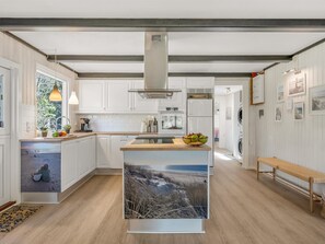 Una cocina moderna con armarios blancos, una isla central y un ventanal grande.