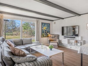 Uma sala de estar moderna com sofá, poltrona, mesa de centro e televisão.