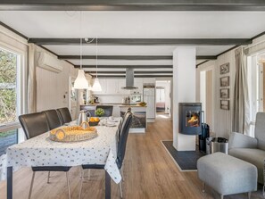 Una cocina moderna con armarios blancos, una isla central y un comedor con una mesa preparada para cuatro.