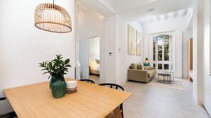 A modern interior with a wooden dining table, a green vase, and a hanging light fixture.