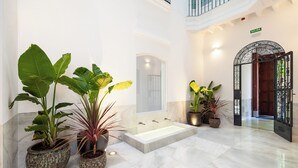 A spacious lobby with a large bathtub, potted plants, and a double door entrance.