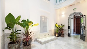 Un hall d’entrée spacieux avec une grande baignoire, des plantes en pot et une porte d’entrée à deux battants.