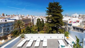 Une terrasse sur le toit, dotée de chaises longues et offrant une vue sur le paysage urbain.