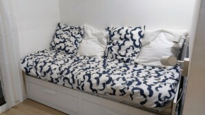A bed with a patterned bedspread and pillows, a bedside table, and a drawer unit. - Studio Notre Dame - Terrace & A/C (Marseille)