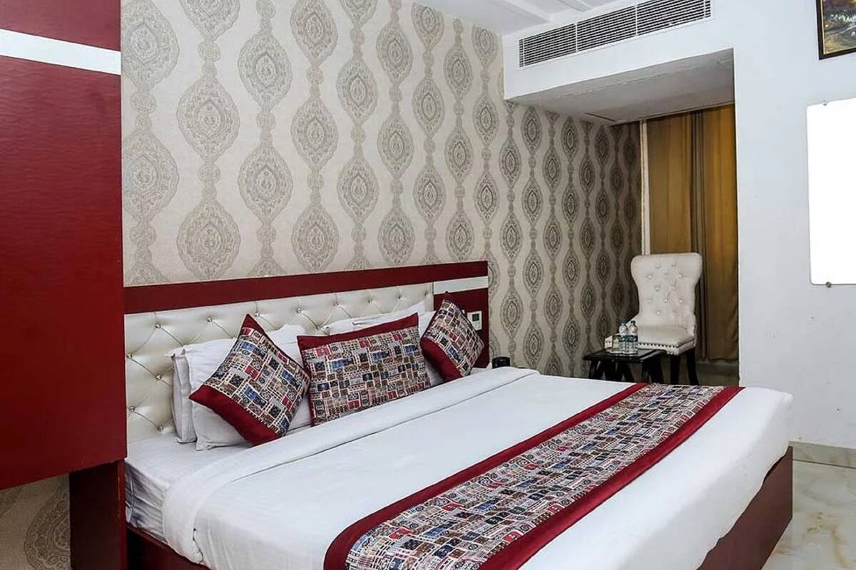 A neatly arranged bedroom with a bed, a ceiling fan, and a patterned wall.