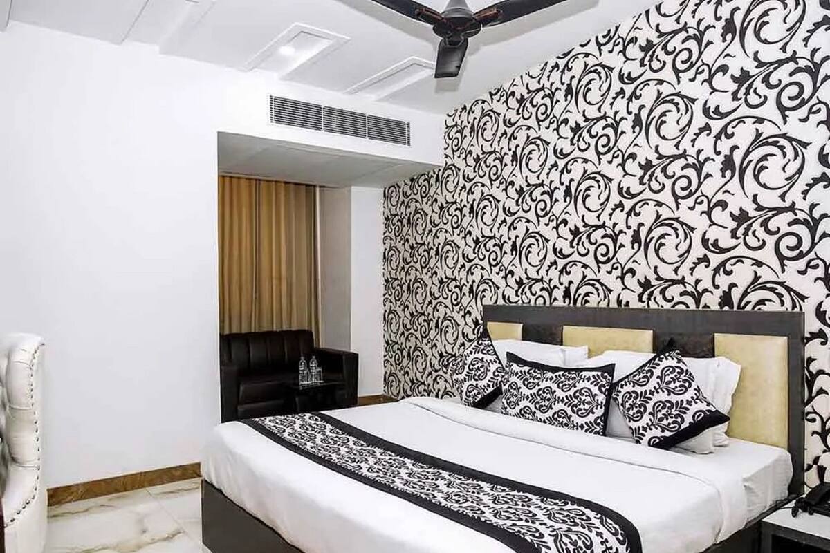 A modern bedroom with a large bed, a ceiling fan, and patterned wallpaper.