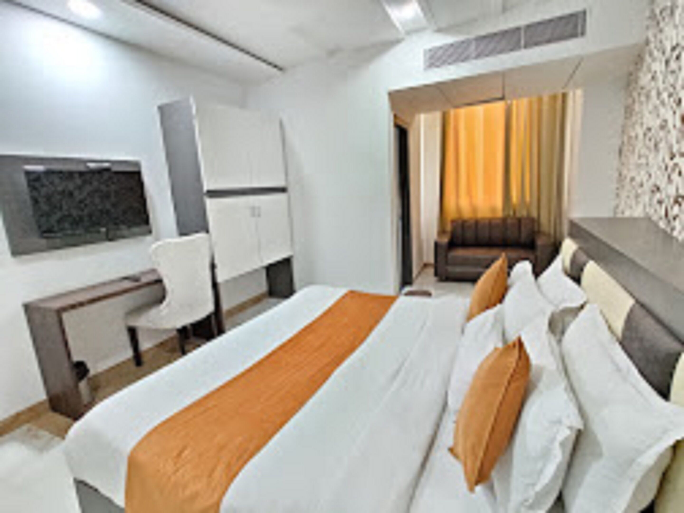 Una habitación de hotel con cama, escritorio, silla y sofá.