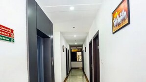 A corridor with doors on both sides, a marble floor, and a ceiling with recessed lighting. - Hotel A Star-50m away from Golden Temple (Amritsar)