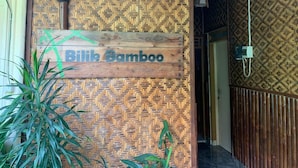 A wooden sign with the text "Bilik Bamboo" against a bamboo-patterned wall. - Bilik Bamboo Homestay (Yogyakarta)