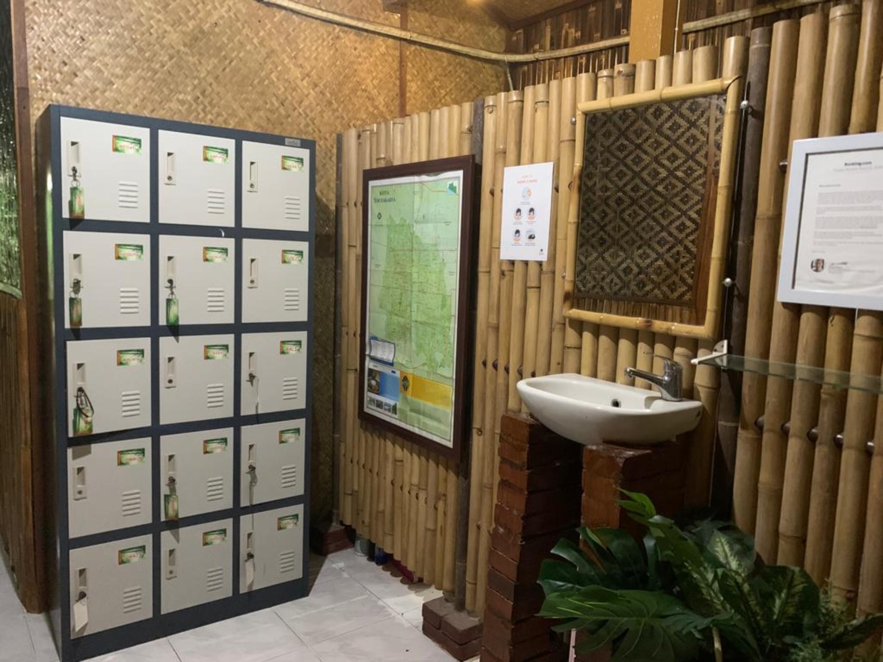 Un baño con varios casilleros, un lavabo, un mapa y un llamativo revestimiento de bambú.