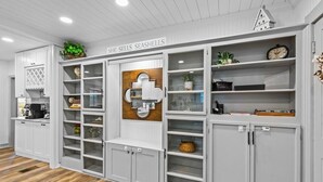 Eine Küche mit weißen Schränken, einer Holzrückwand und einem Schild mit der Aufschrift 'She sells seashells'.