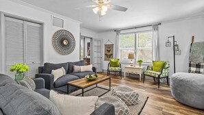 Ein Wohnzimmer mit grauem Sofa, einem Couchtisch und einem gemusterten Teppich.