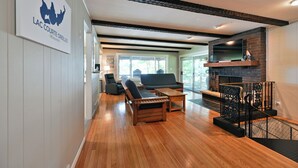 Un amplio salón con suelo de madera, un sof á, una mesa de centro y una chimenea.