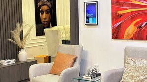 A modern living room with two armchairs, a glass coffee table, a decorative vase, and a framed abstract painting. - Fully fitted 2 bedroom smart luxury apartment. (Abuja)