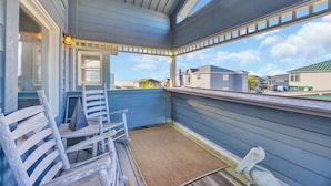 Un espace extérieur abrité, doté d’une terrasse en bois, d’un banc et offrant une vue sur les maisons voisines.