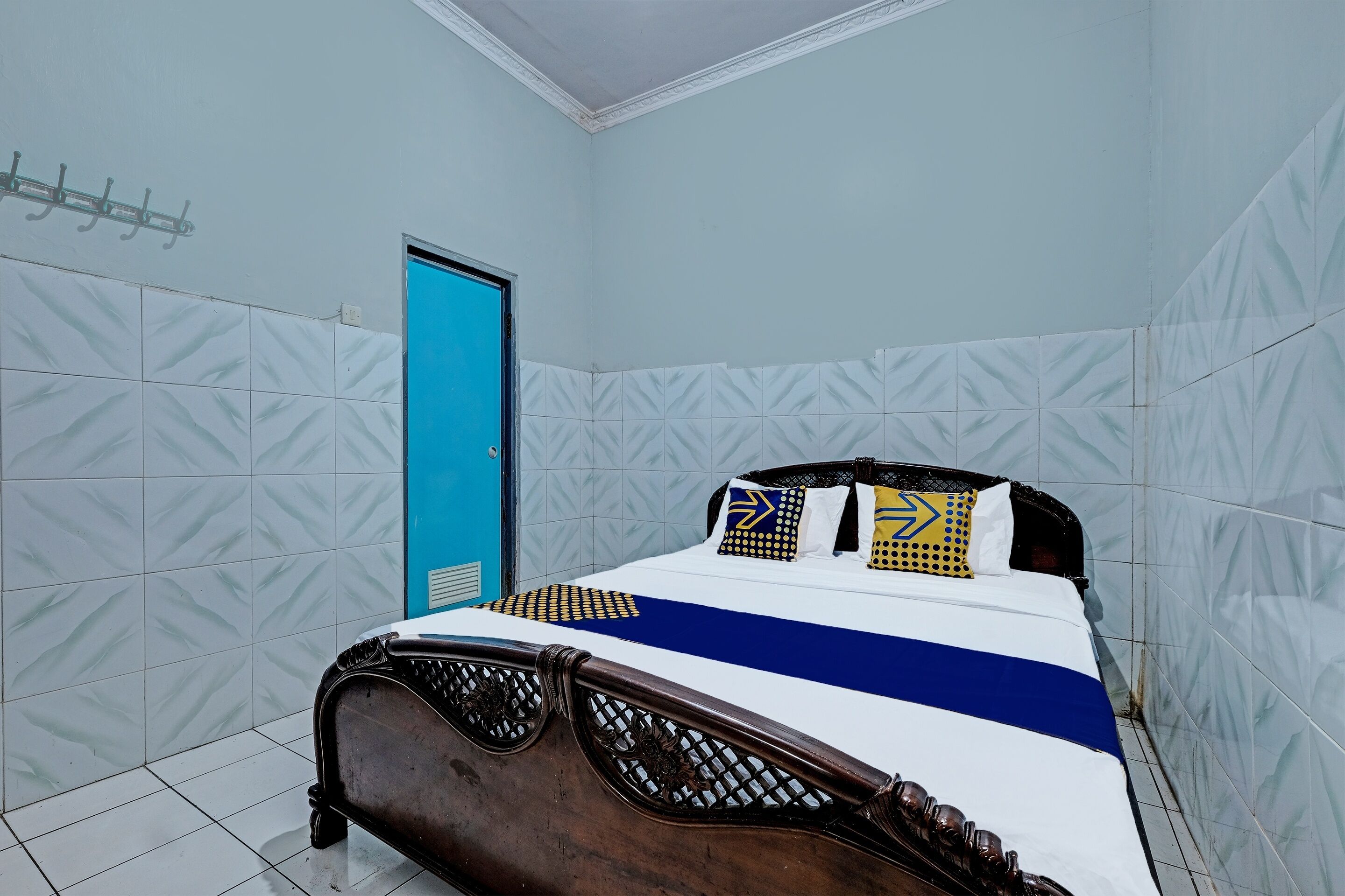 Quarto com cama, porta azul e paredes com padrão.