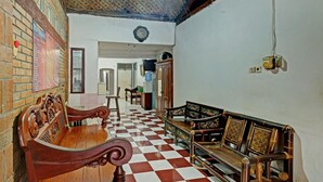 Een kamer met een zwart-wit geruite vloer, houten meubels, een klok aan de muur en een menubord.