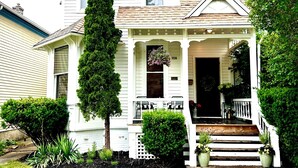 A two-story house with a front porch, a tall evergreen tree, and a well-maintained lawn. - LUX Uptown Escape - The Trester
 (Sheboygan)