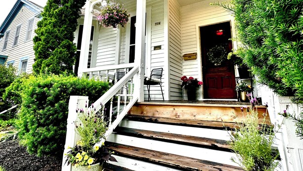A white house with a porch, wooden steps, and potted plants. - LUX Uptown Escape - The Trester
 (Sheboygan)