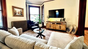 A living room with a sofa set, a coffee table, a TV, and a radiator. - LUX Uptown Escape - The Trester
 (Sheboygan)