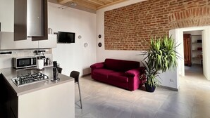 Une cuisine moderne avec un îlot central, un canapé rouge et un mur en briques.