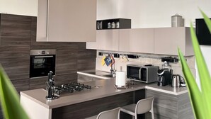 Une cuisine moderne dotée d’un îlot central, d’appareils électroménagers en acier inoxydable et d’un plafond en bois.