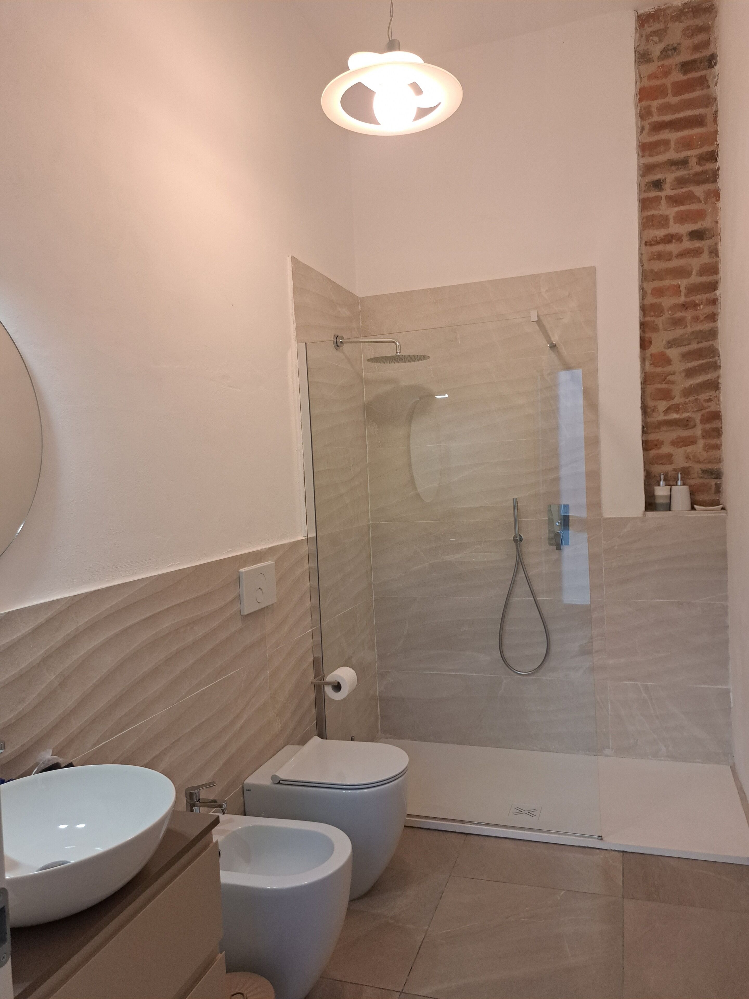 A modern bathroom with a glass-enclosed shower, a white sink, and a bidet.