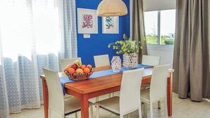 A dining area with a wooden table, white chairs, a blue tablecloth, and a basket of fruit. - Villa Elena Coral (Pegeia)
