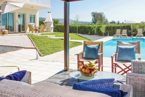 Ein Sitzbereich im Freien mit Pool, Korbmöbeln und einer Obstschale.