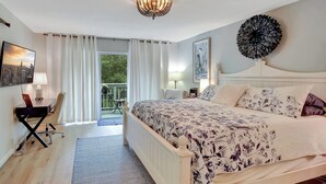 Une chambre avec un grand lit, un lustre, une vue sur l’extérieur et un balcon.